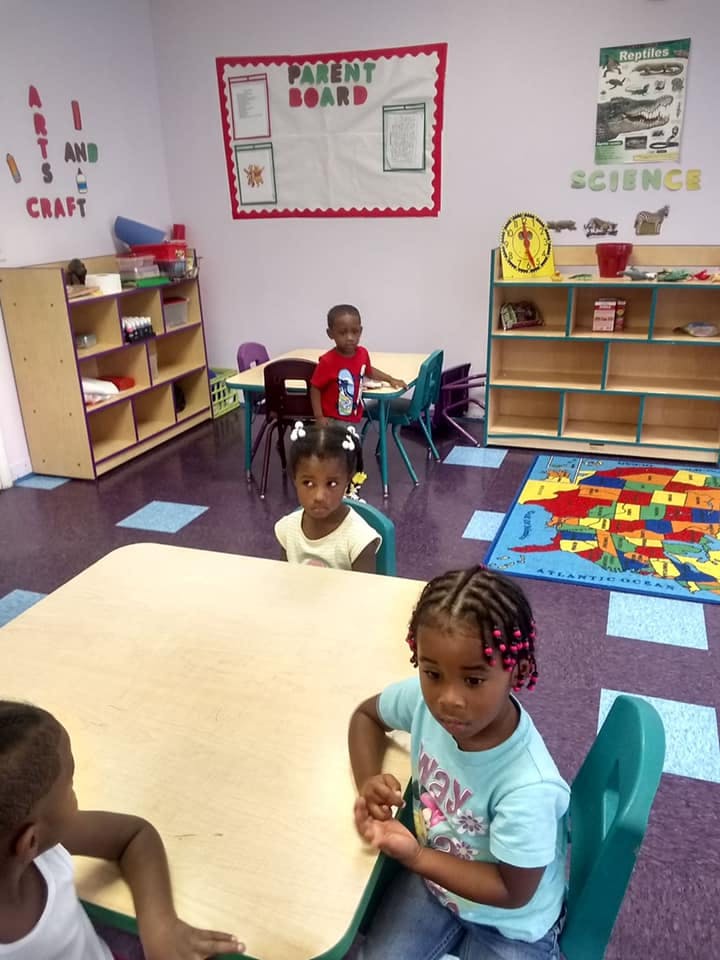 Three children sitting at tables in a classroom