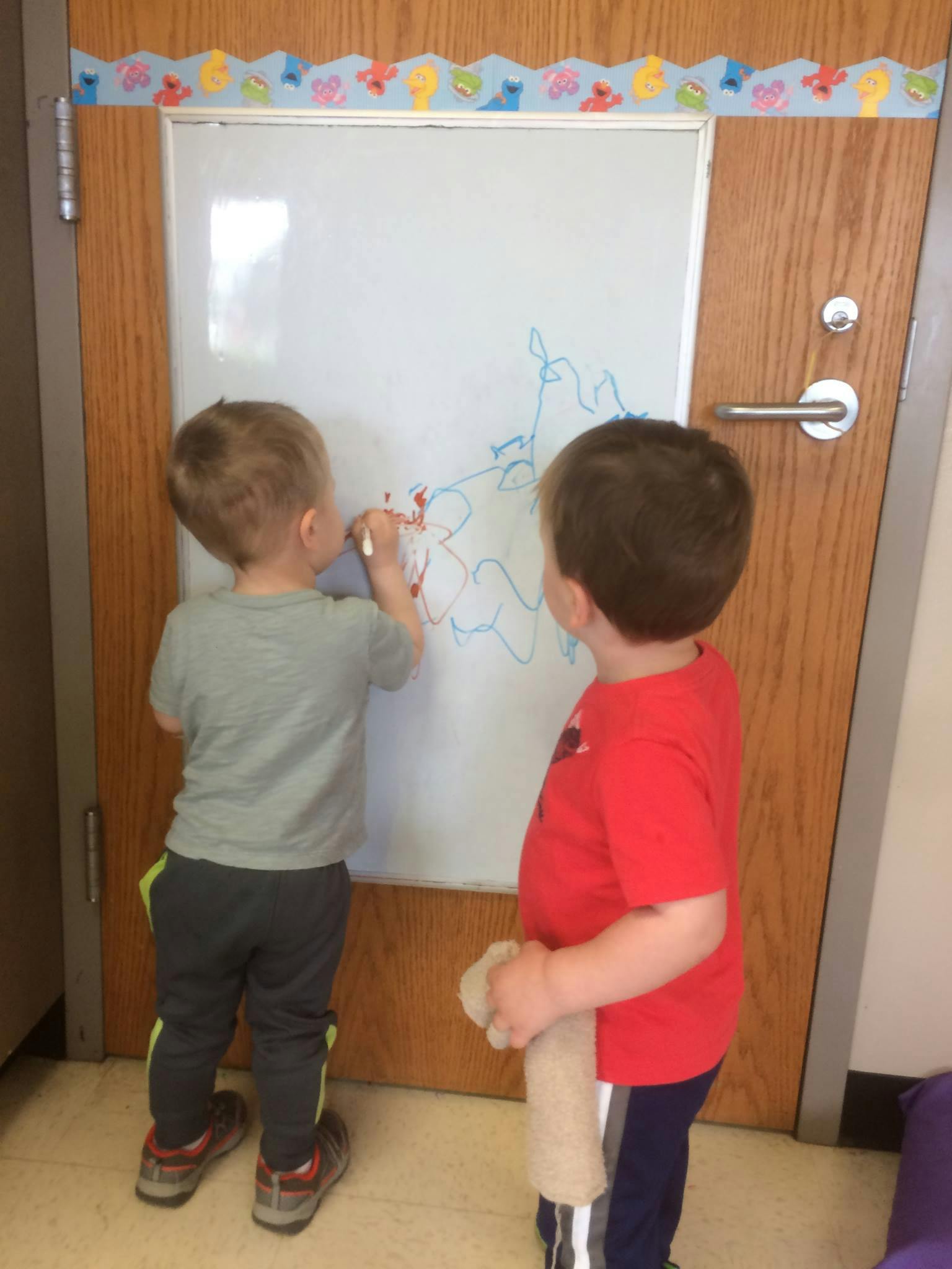 Two children drawing on a whiteboard