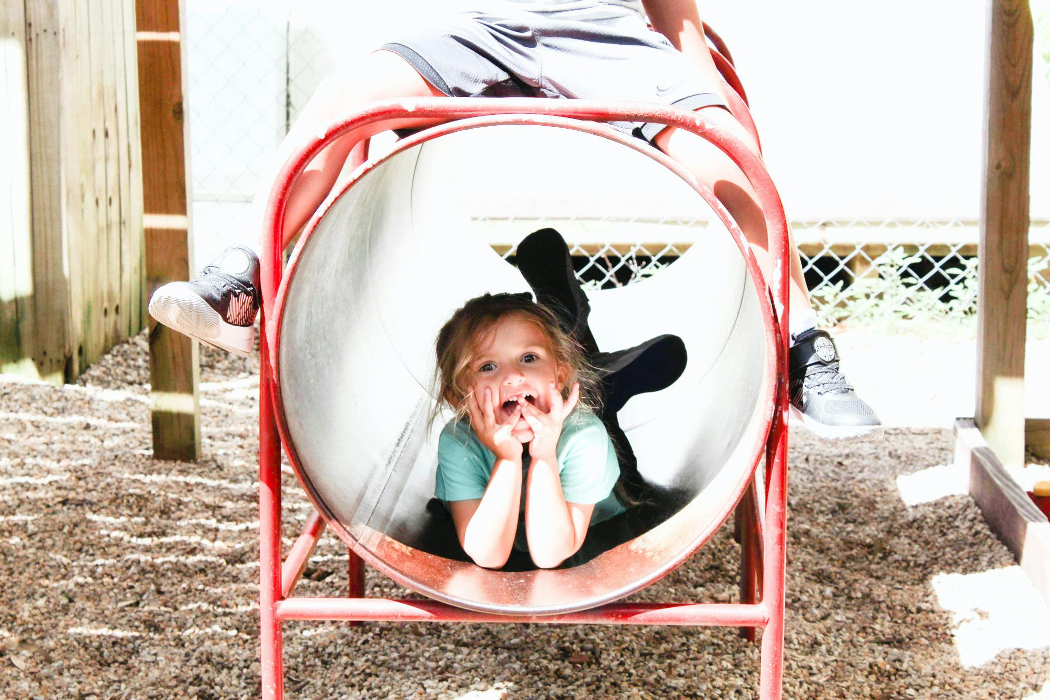 Child looking out from inside a red play tunnel