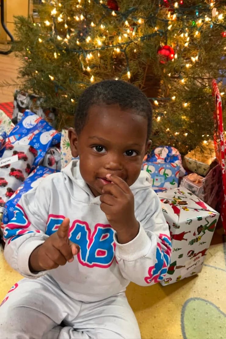 Child sitting in front of a Christmas tree with presents