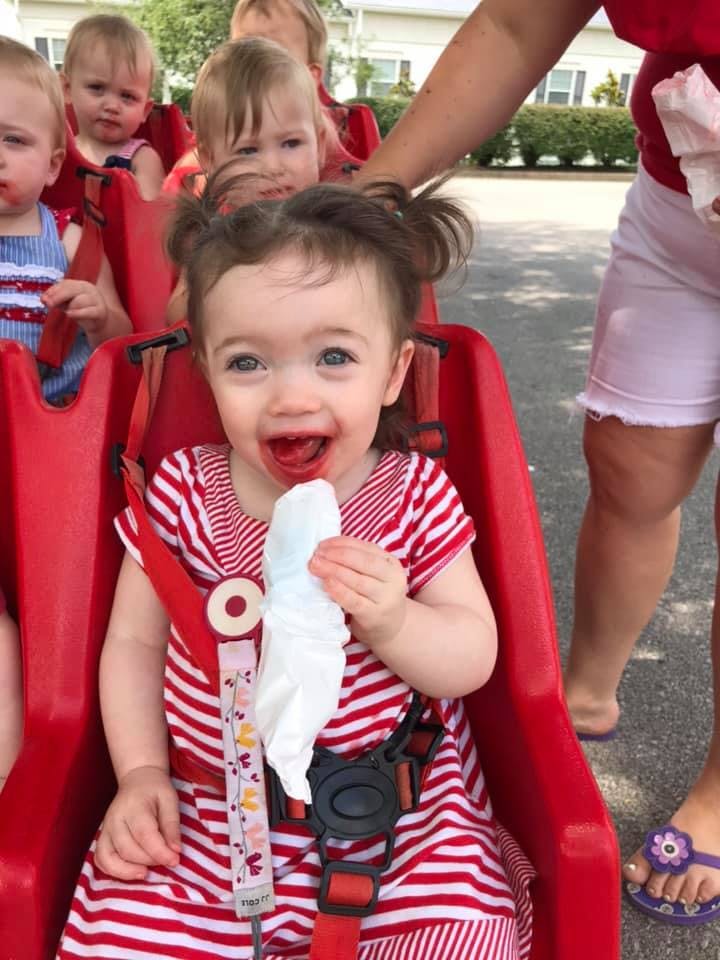 Child in red and white striped dress with red around mouth, holding a tissue