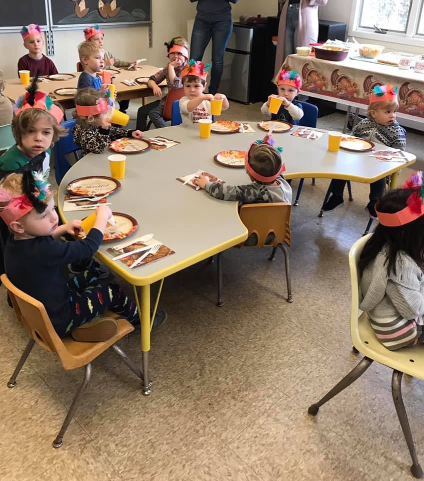 Children sitting at tables with plates and cups