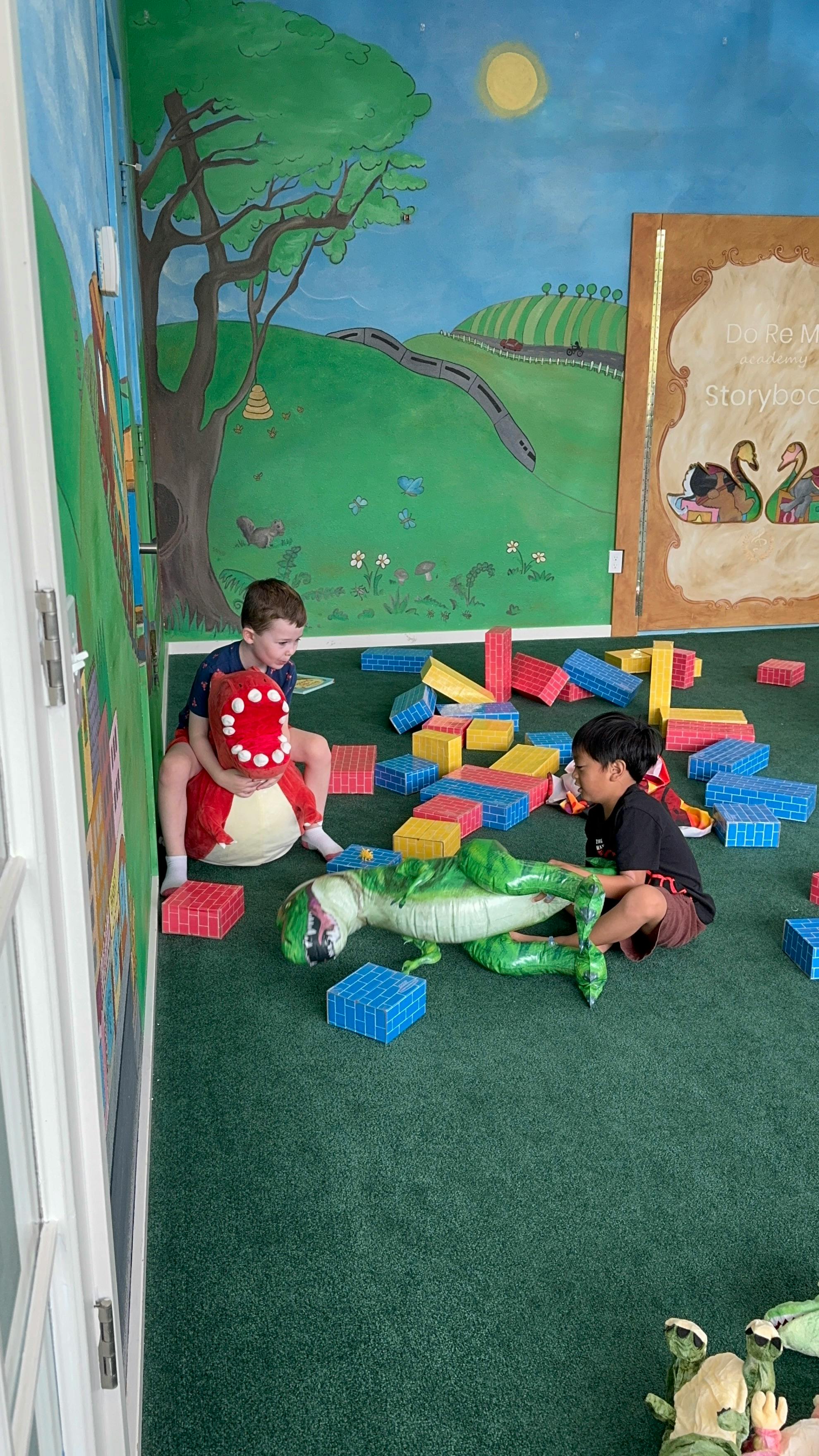Two children playing with dinosaur toys and building blocks in a room