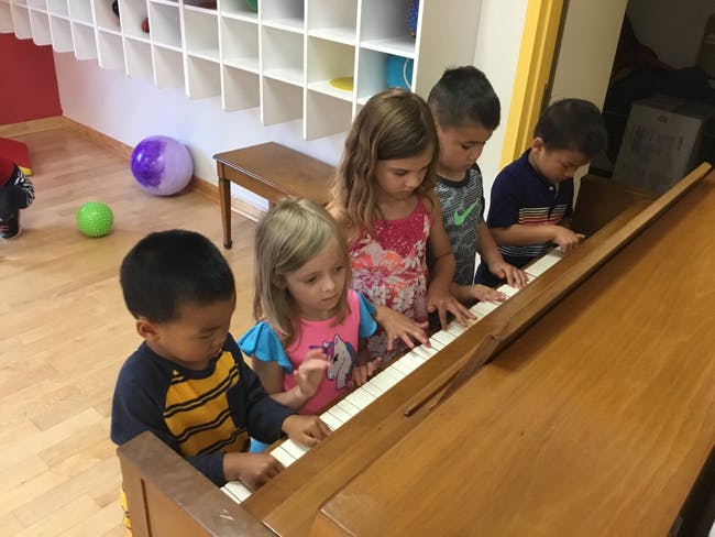 Four children playing a piano