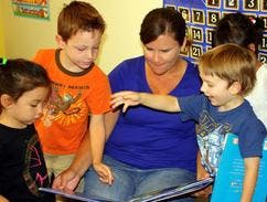 Adult and three children looking at a book
