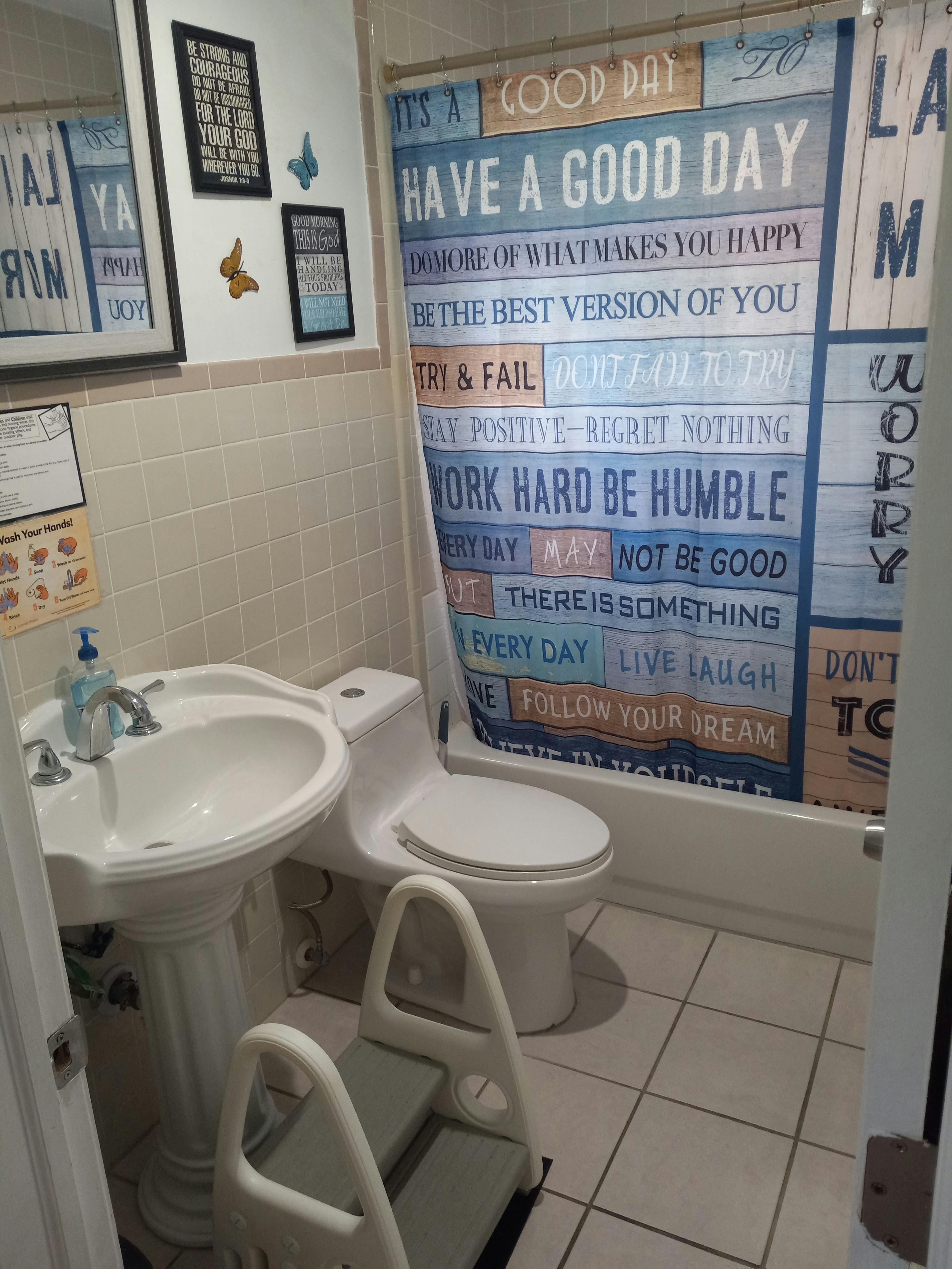 Bathroom with a sink, toilet, and shower curtain with text