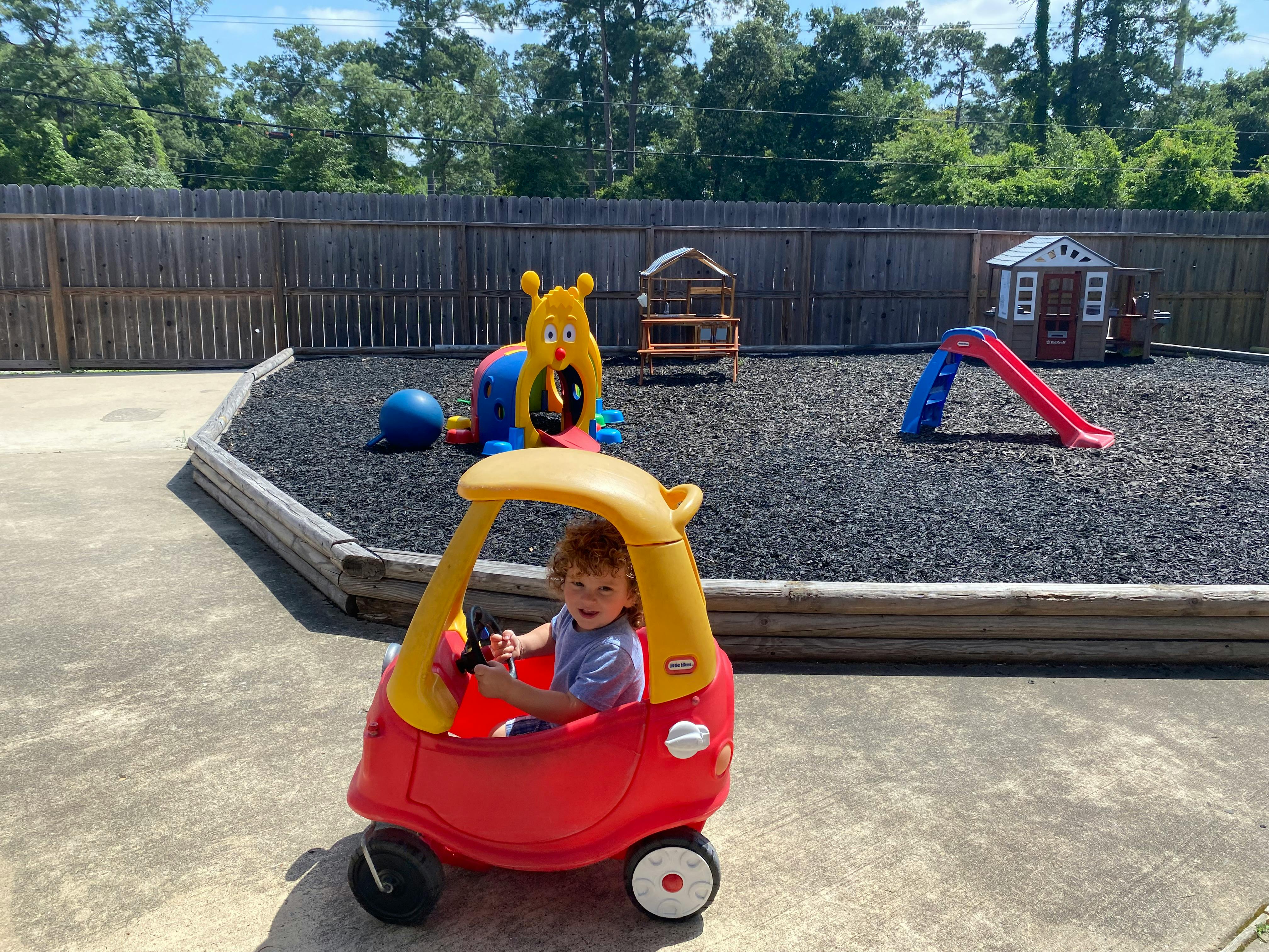 Child in a red toy car on a playground