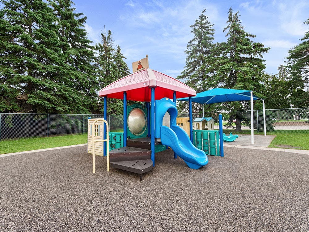 Playground with blue slide and red canopy surrounded by trees