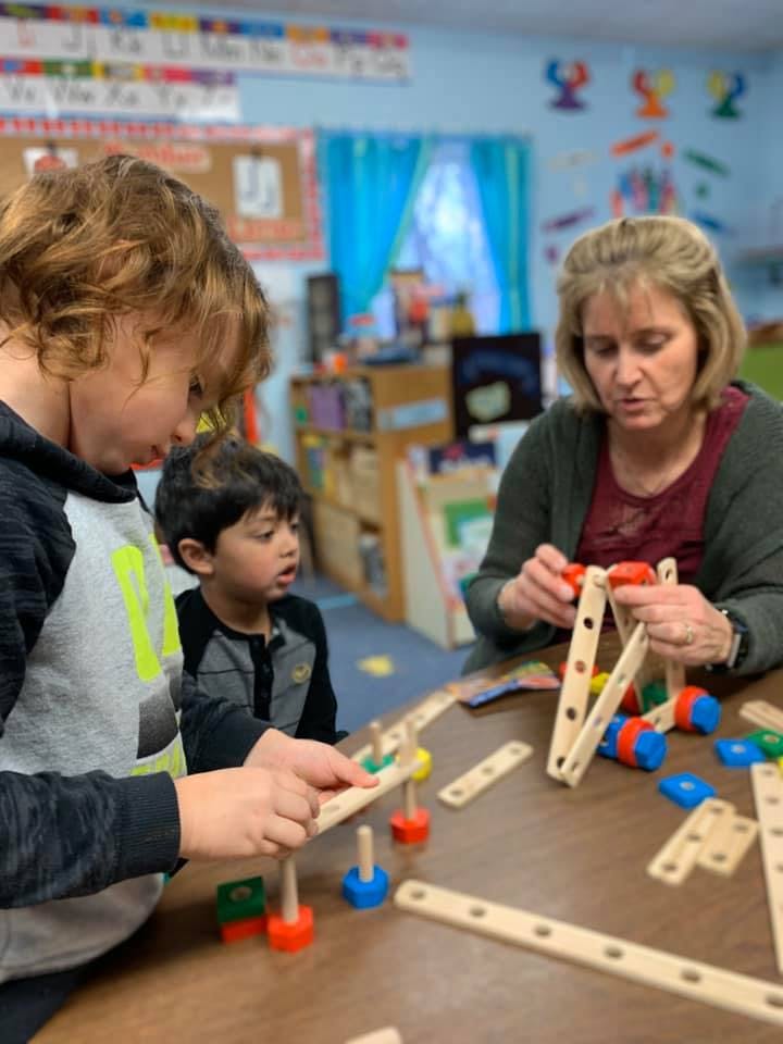 Adult and two children building with wooden and plastic construction toys
