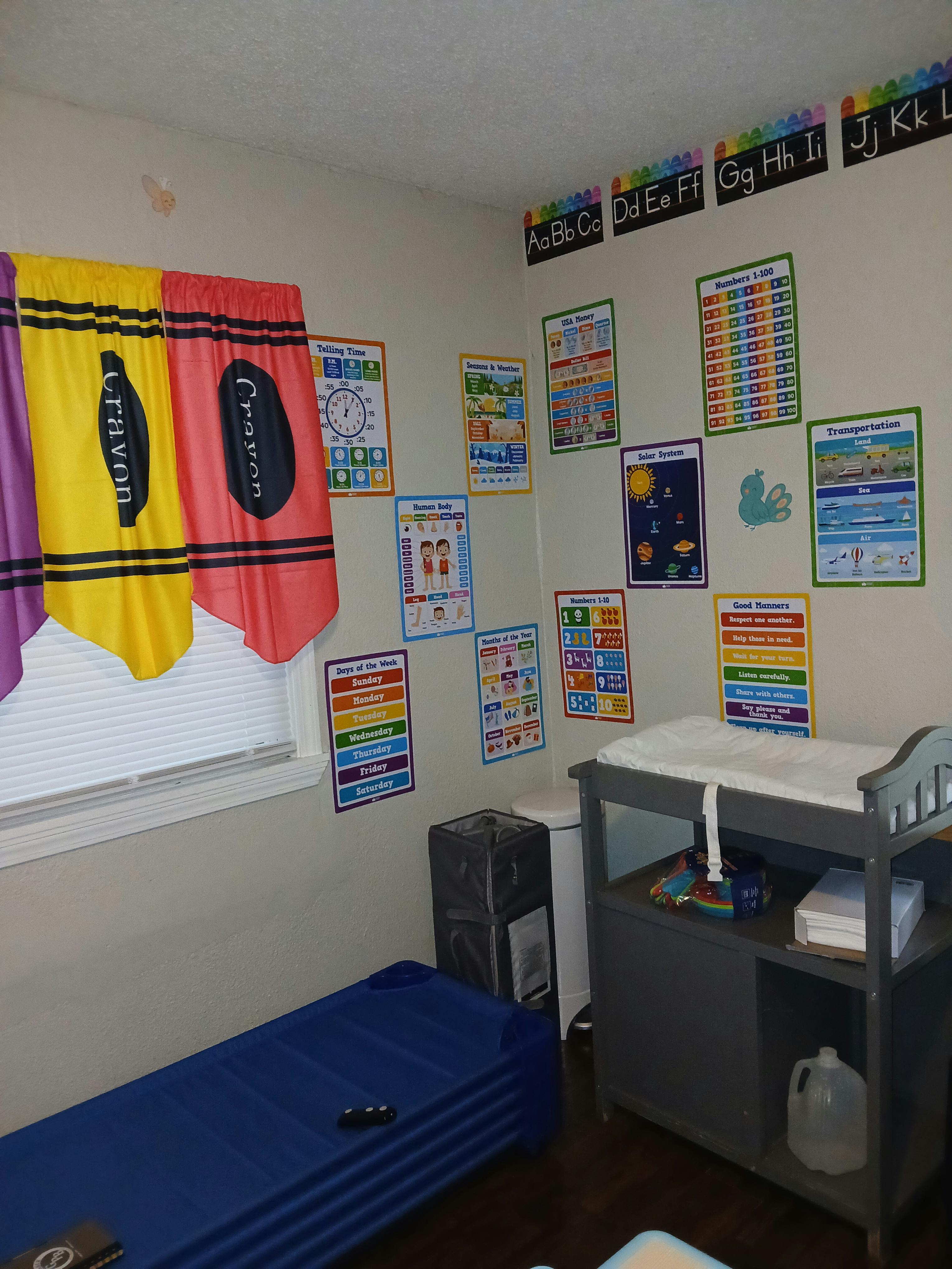 Classroom with educational posters, crayon curtains, and a changing table