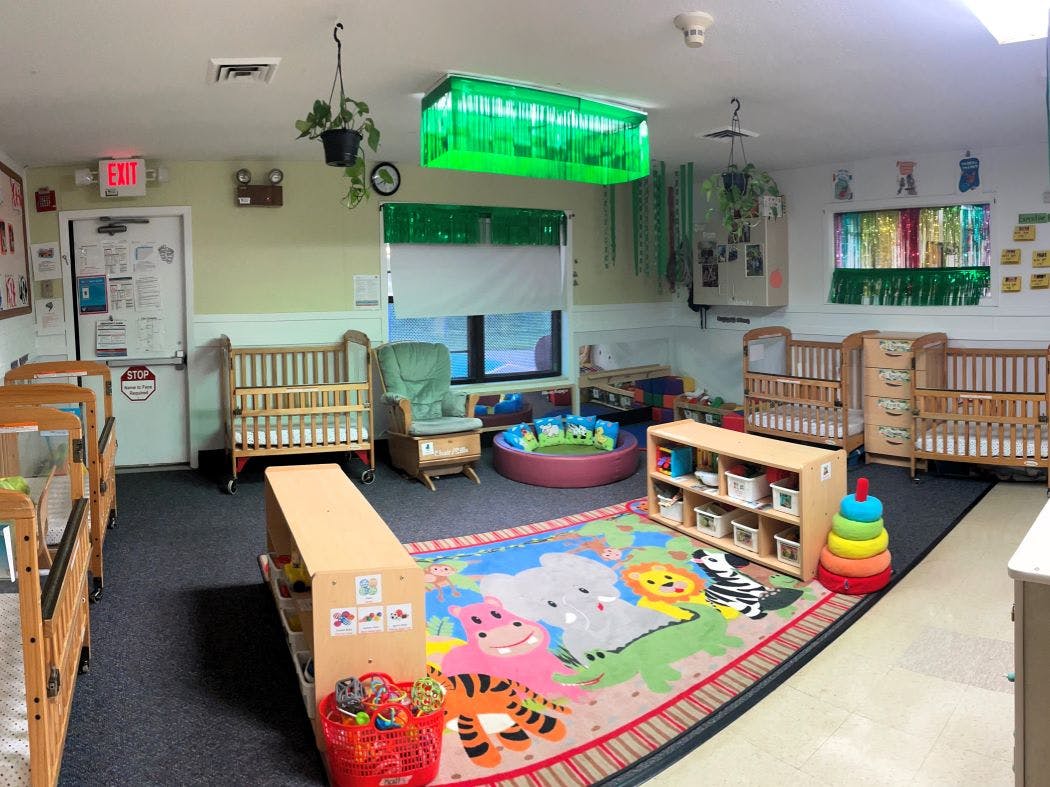 cribs and play area in a daycare classroom