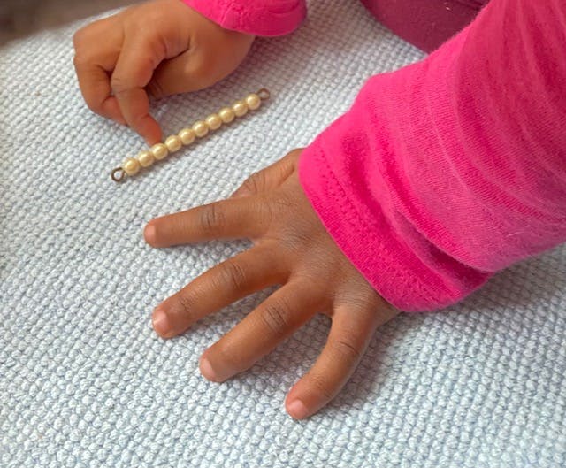 Child's hands touching a string of beads