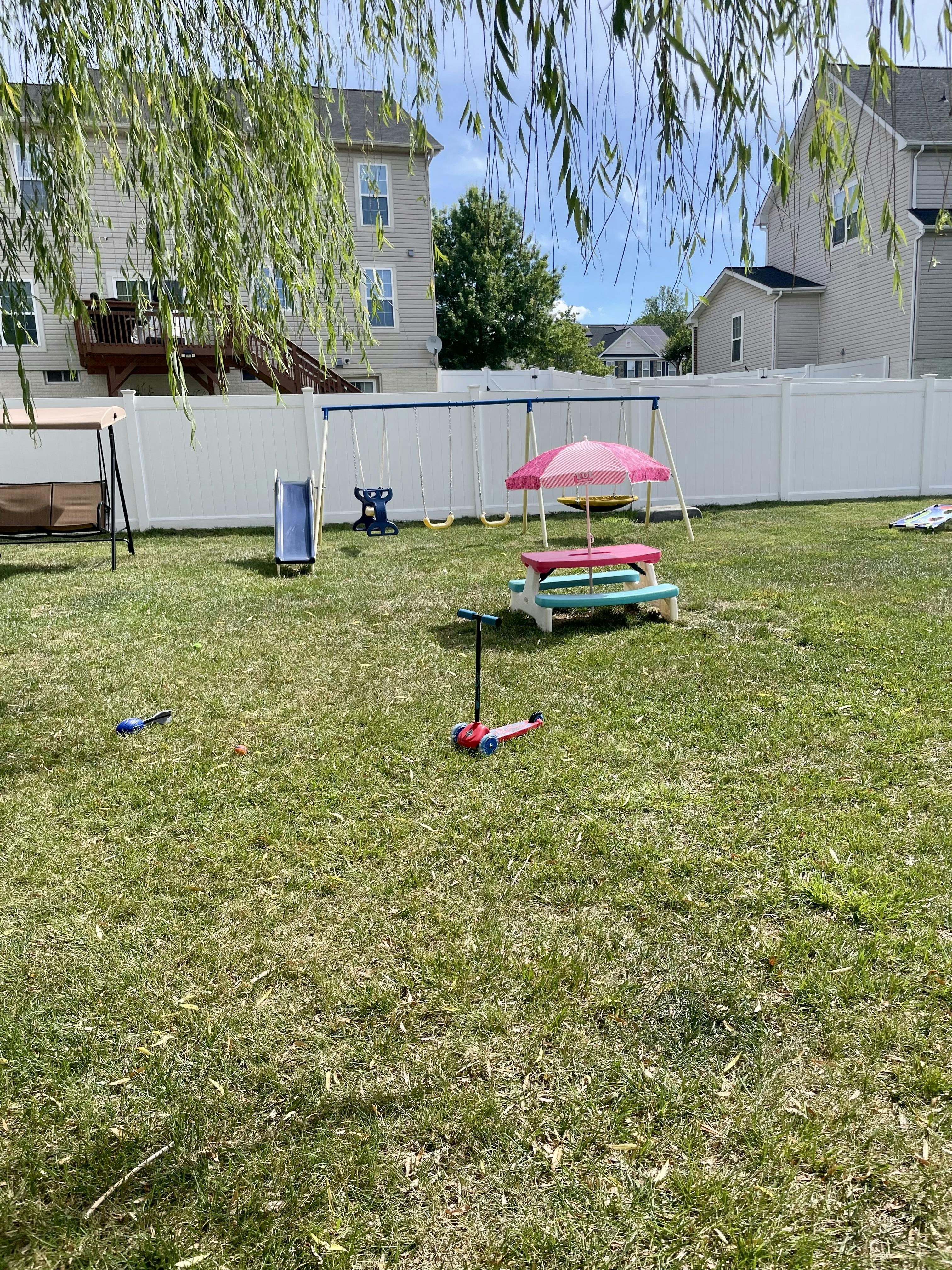 Backyard with a swing set, children's picnic table, and scooter on grass