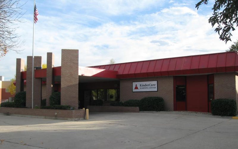 KinderCare Learning Center building with red roof, brick facade, and an American flag