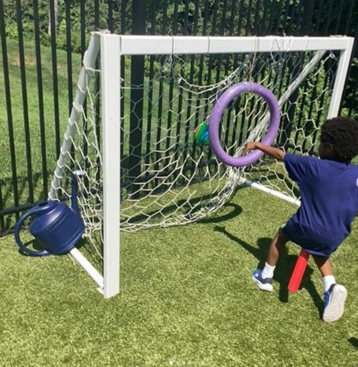 Child playing with a purple ring in front of a soccer goal