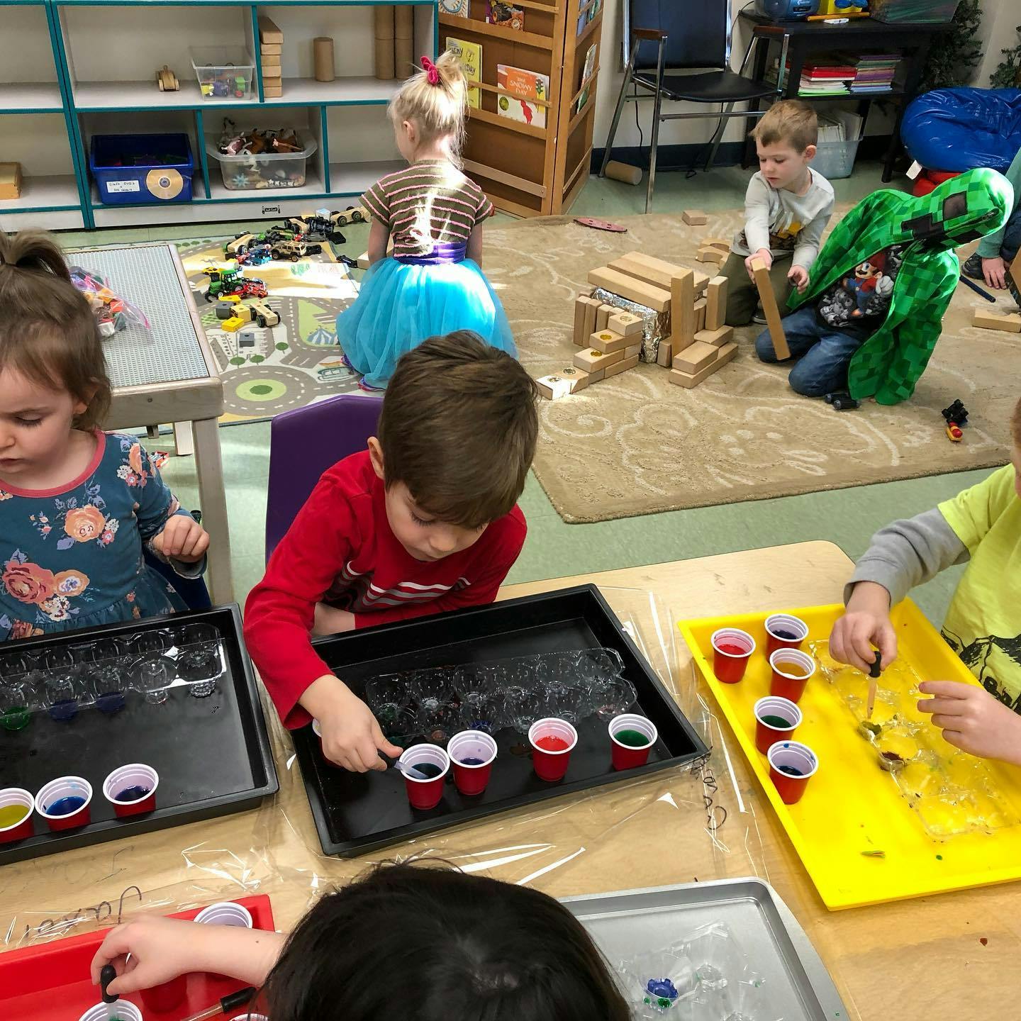 Children playing with colorful liquids and blocks in a classroom
