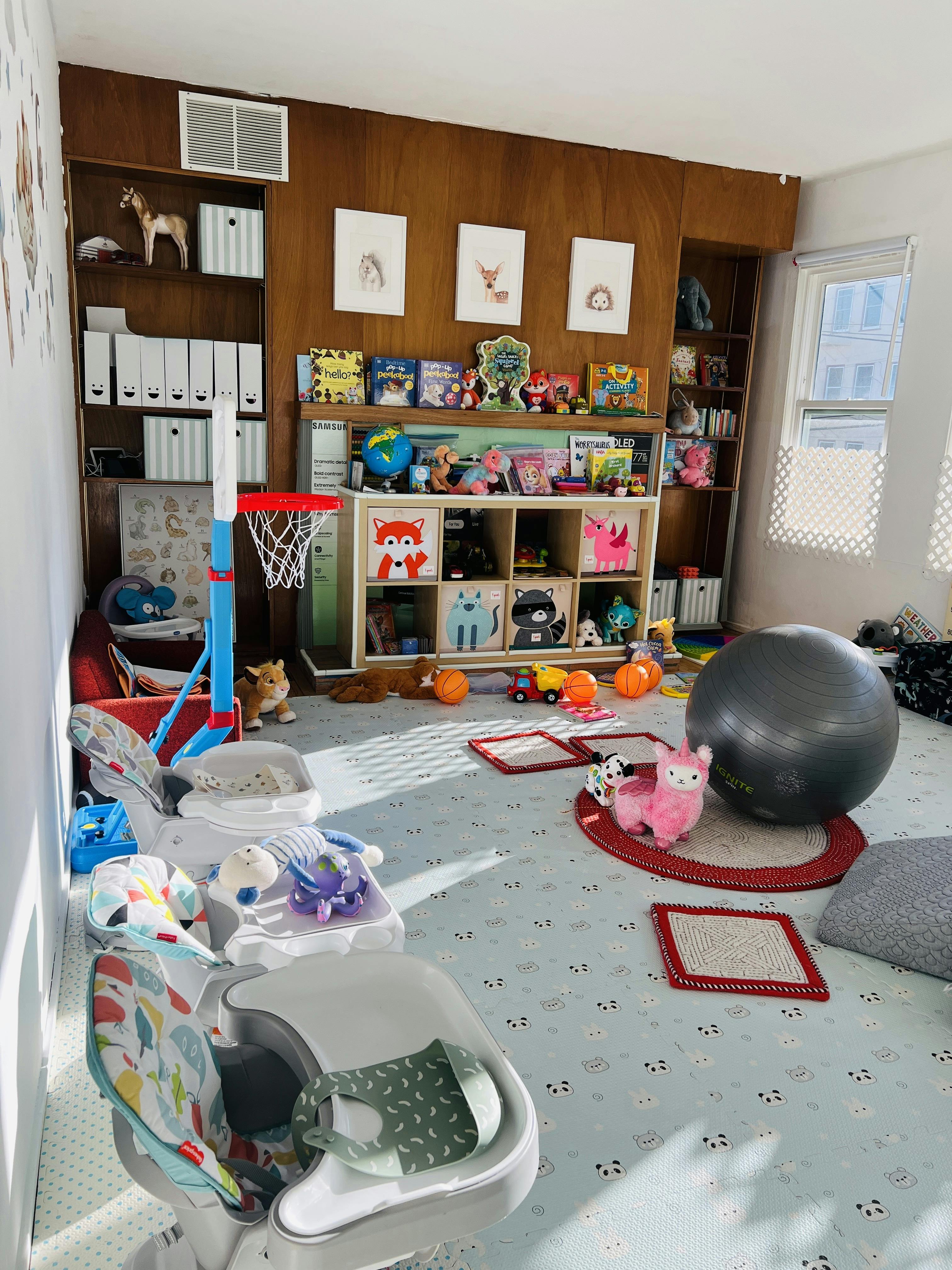 Playroom with children's toys and furniture on a patterned floor mat