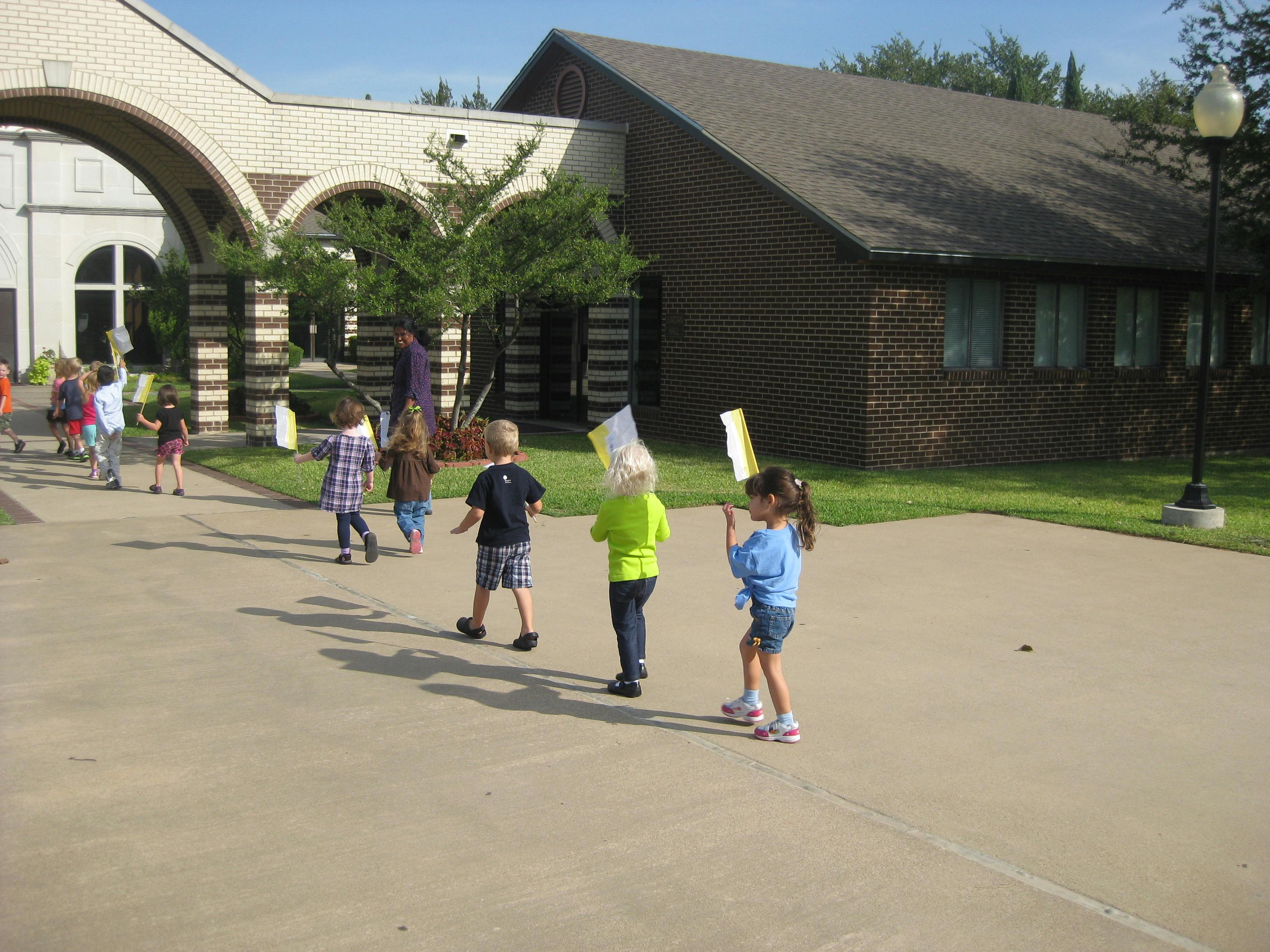 Children walking on a paved area outside a building