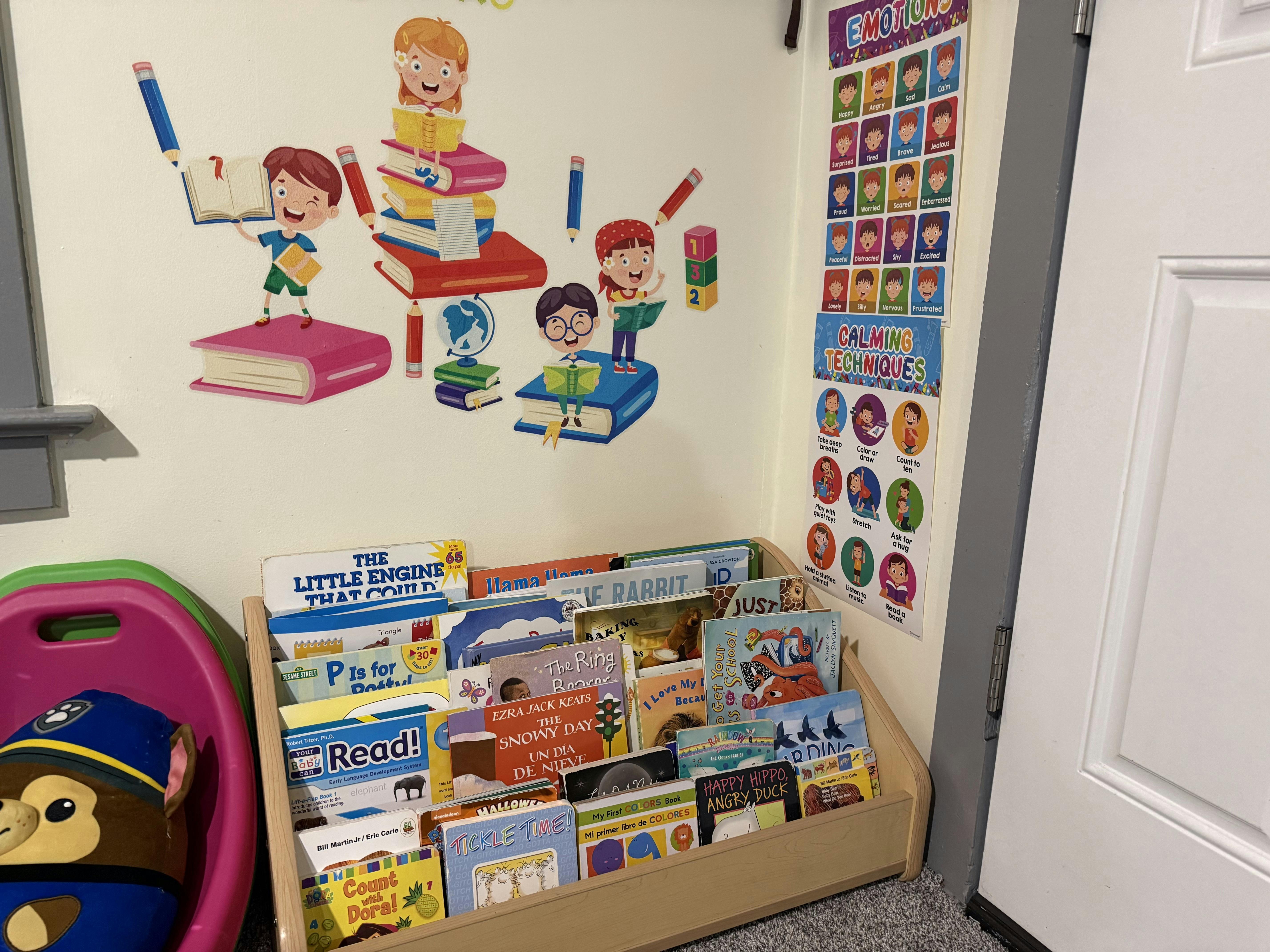 A children's reading nook with a bookshelf full of books, wall decals, and posters