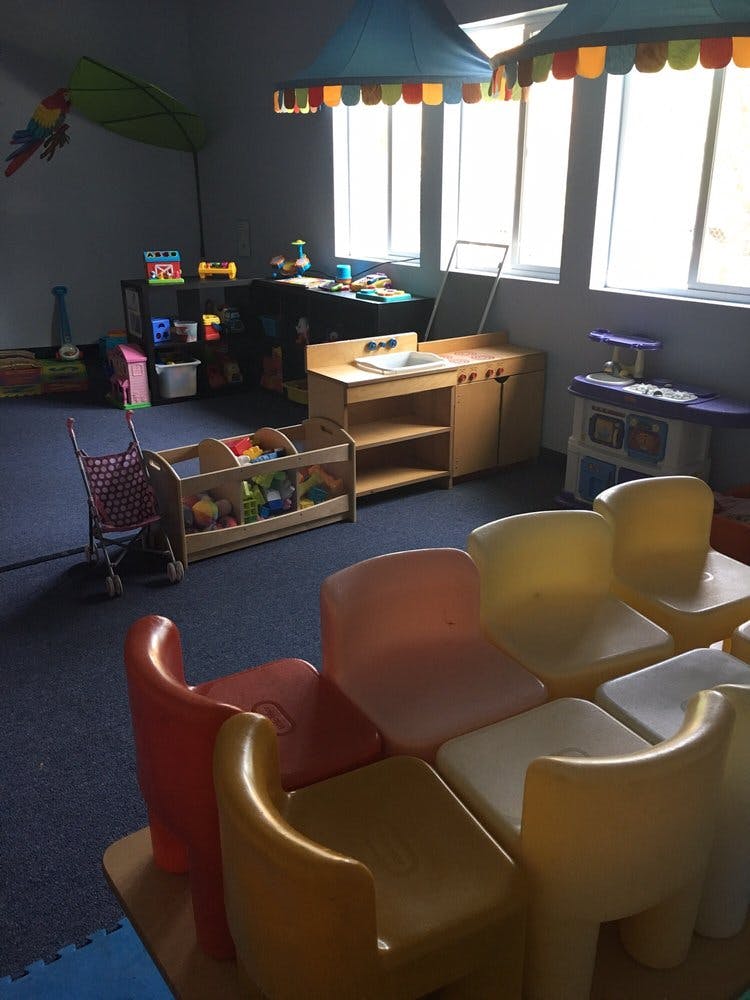 Playroom with small chairs, toy kitchen, and toy storage