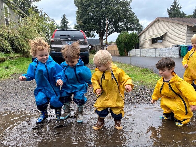 Children in rain gear playing in puddles