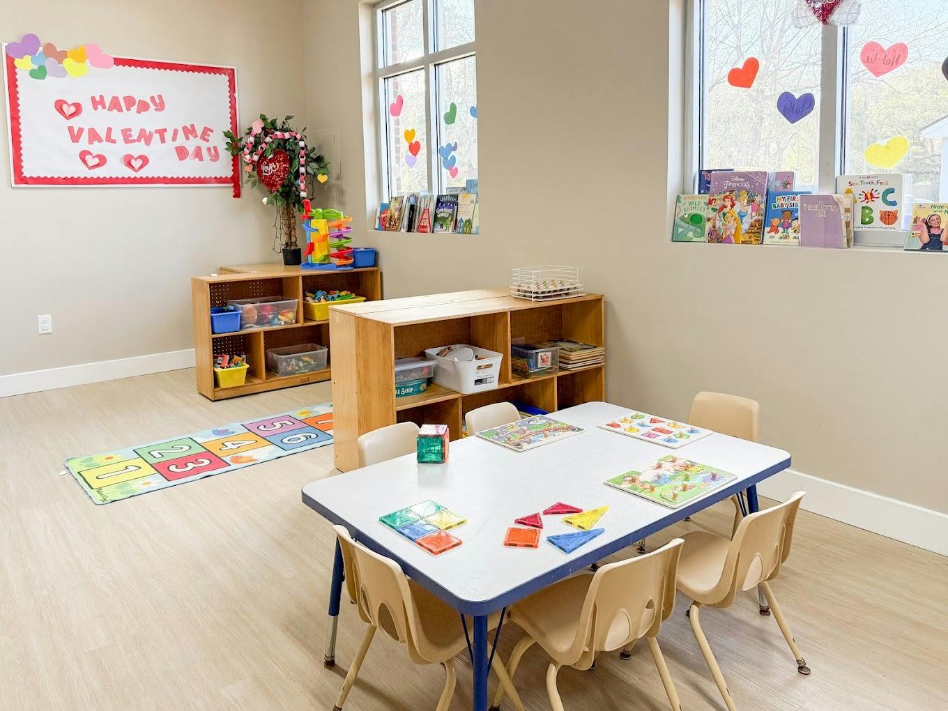Classroom with tables and chairs for children, book shelves, and toy bins