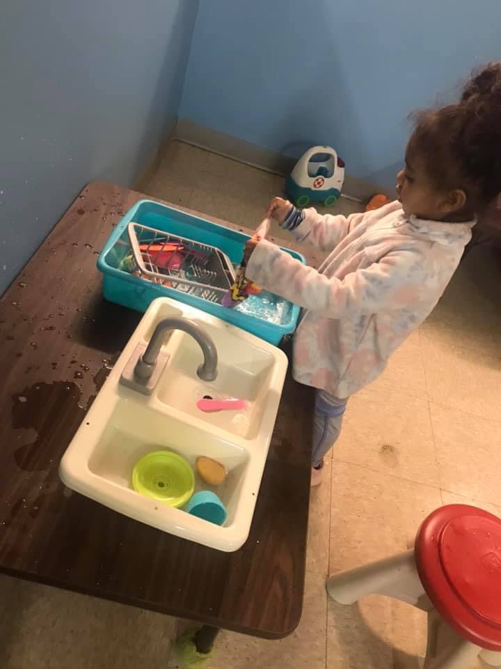 Child playing with a toy sink and dishes