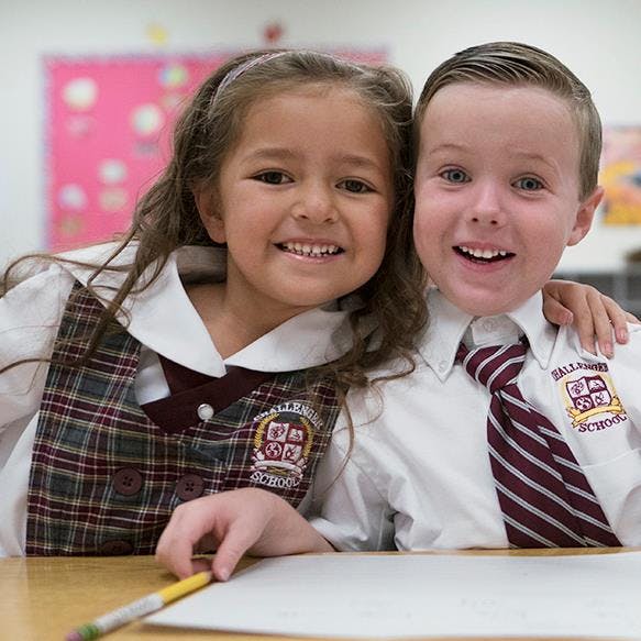 Two children in school uniforms smiling