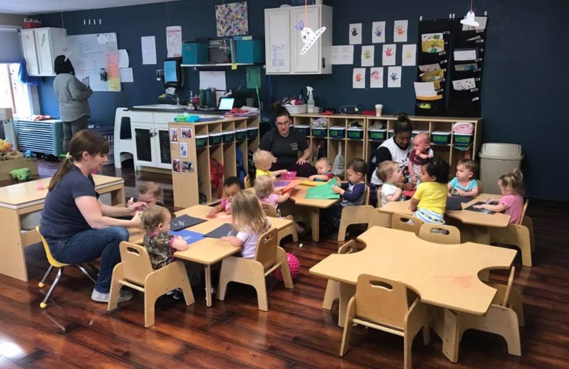 Adults and children sitting at tables in a classroom