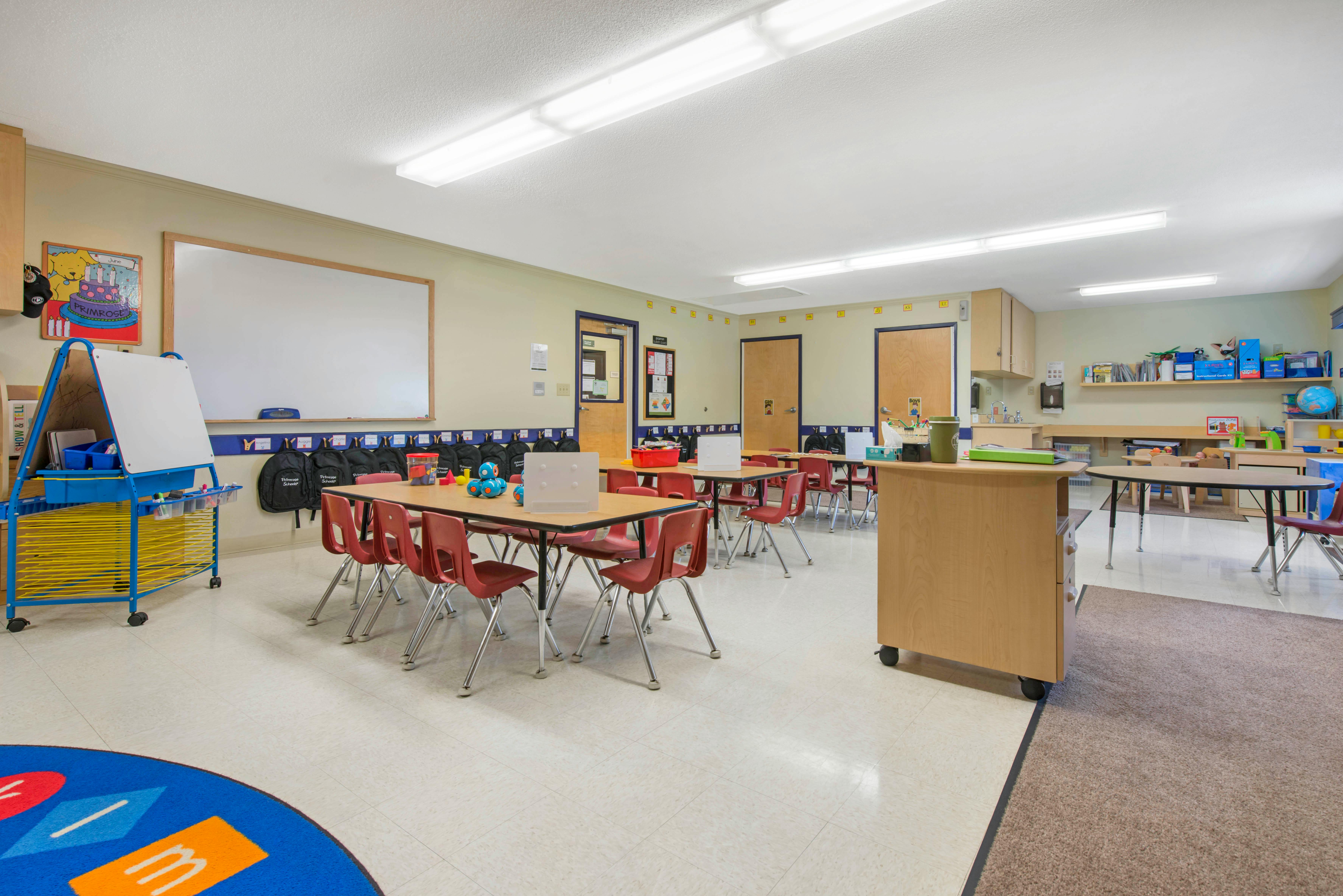 Classroom with tables, red chairs, and a whiteboard