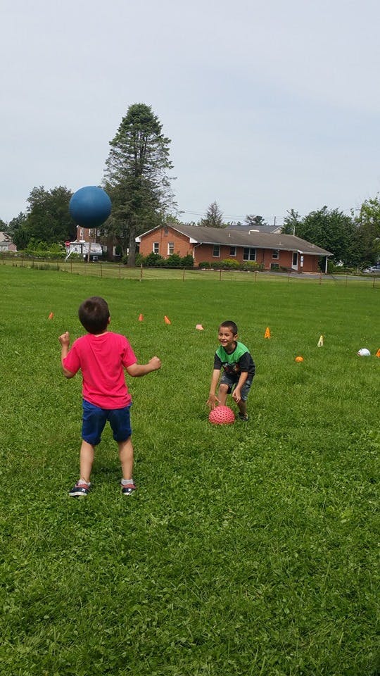 Two children playing with balls in a grassy field