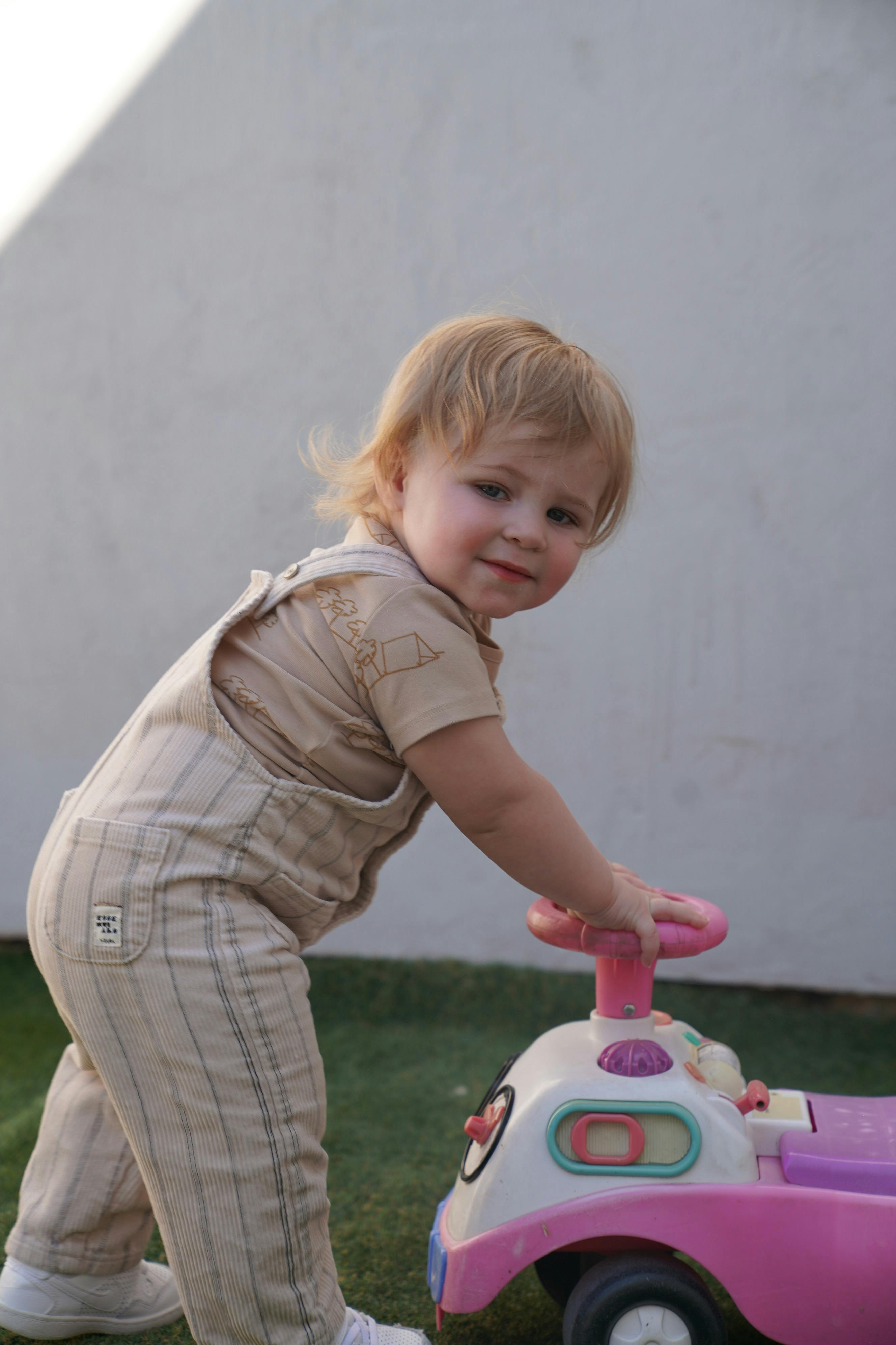 Child standing next to a toy car