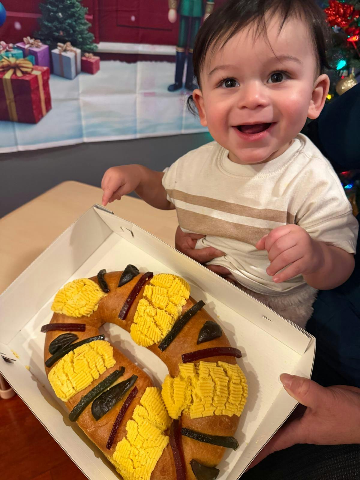 Child sitting behind a ring-shaped pastry in a box
