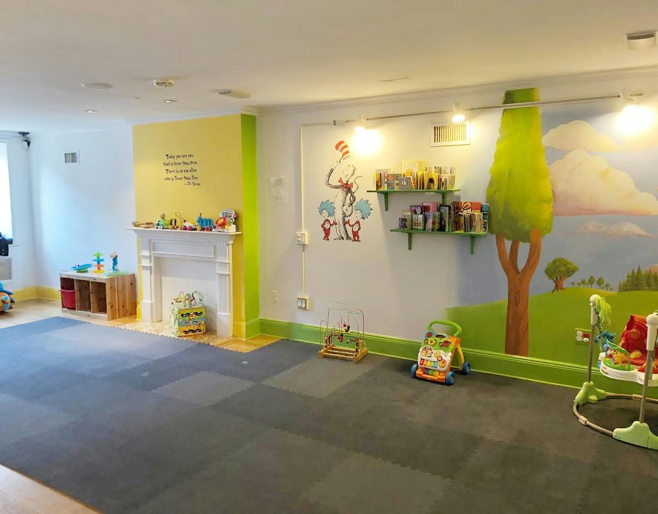 Playroom with colorful wall murals, toys, and a fireplace