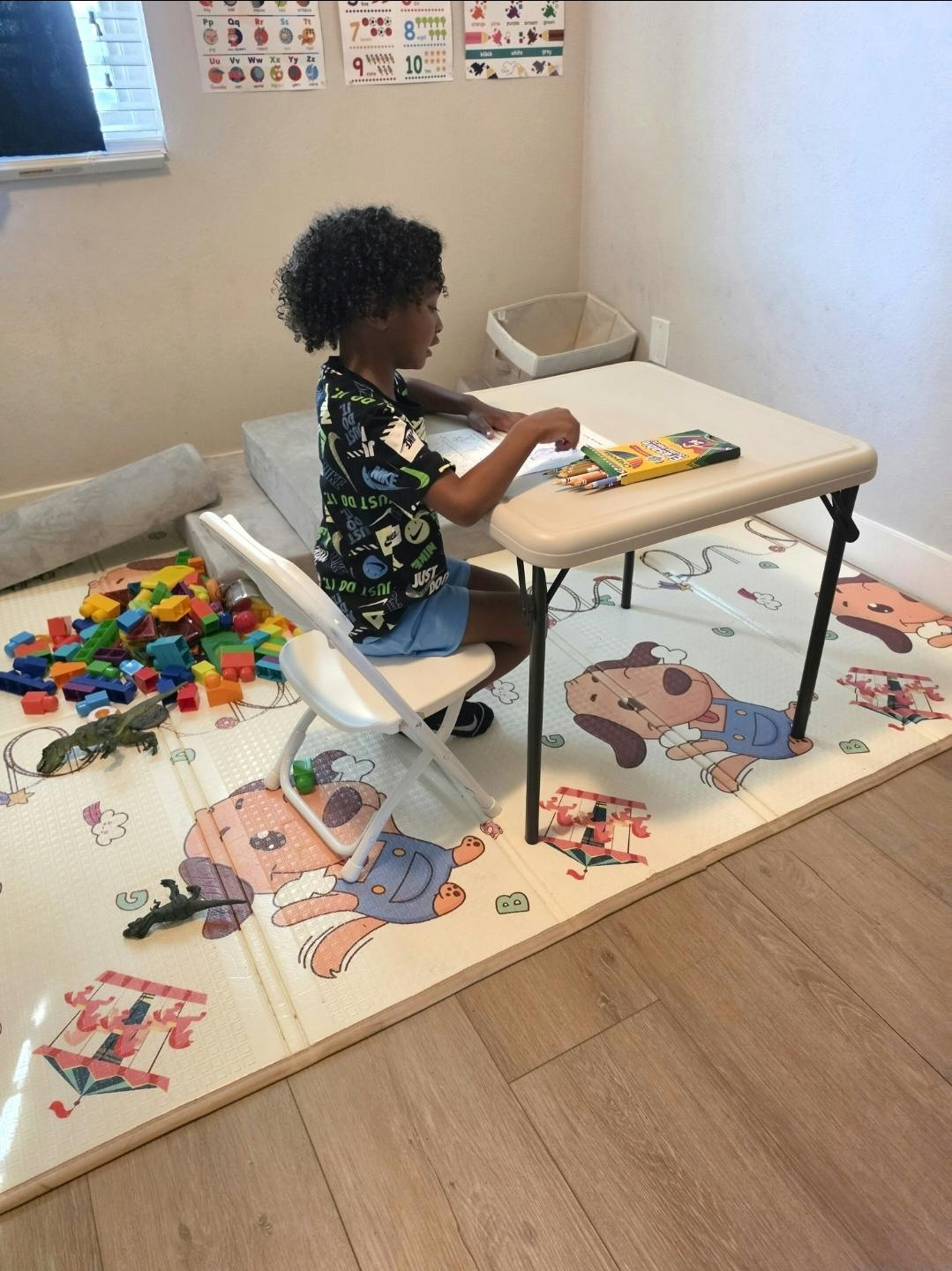 Child sitting at a small table, coloring with crayons