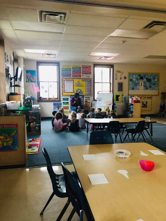 Person reading to children sitting on the floor in a classroom