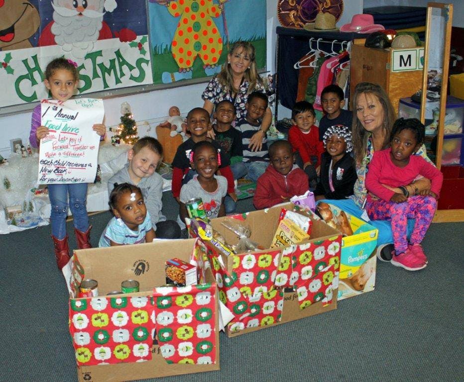 Two adults and multiple children with boxes of donations