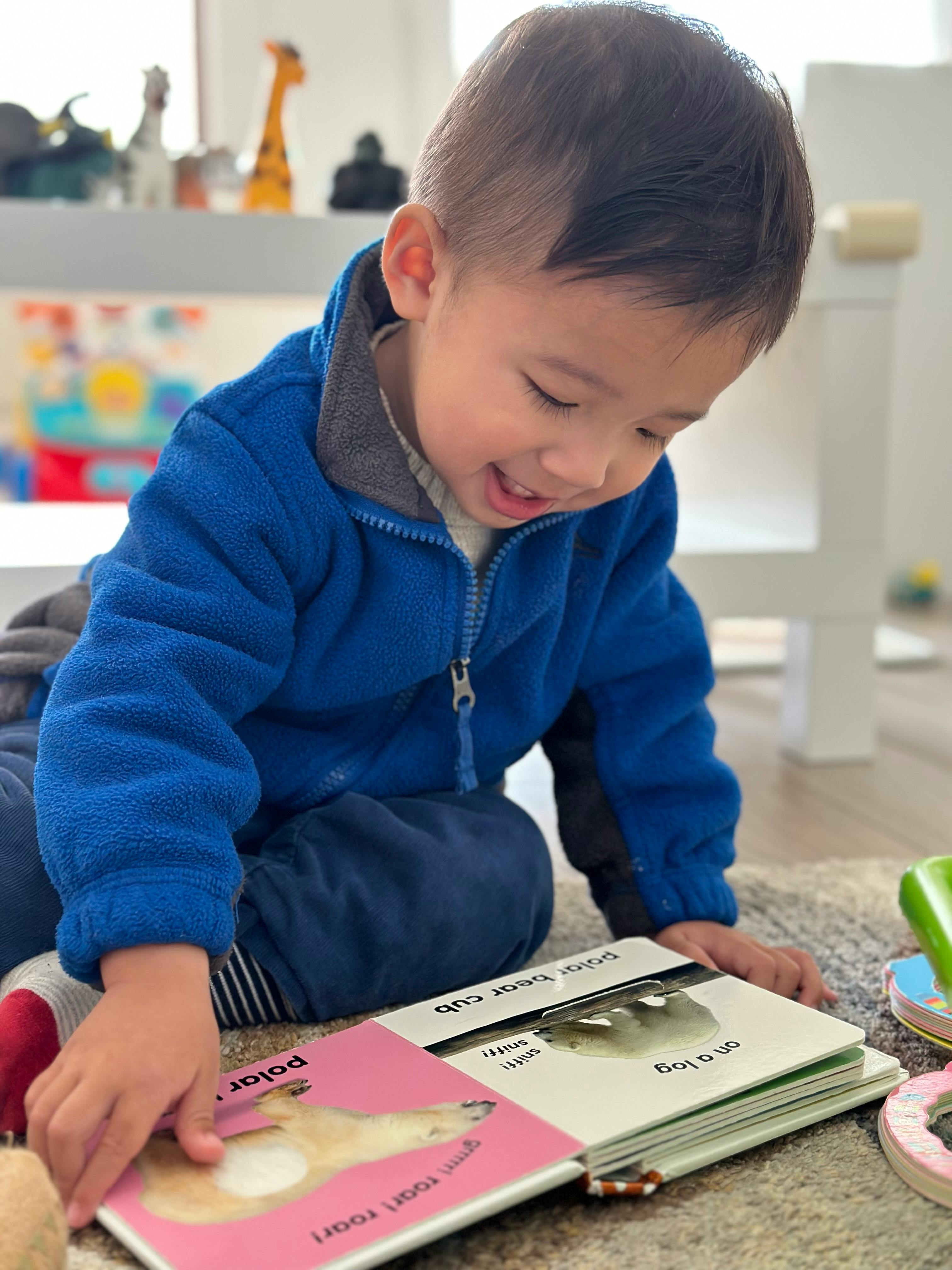 Child in blue jacket looking at a book with a polar bear on the cover