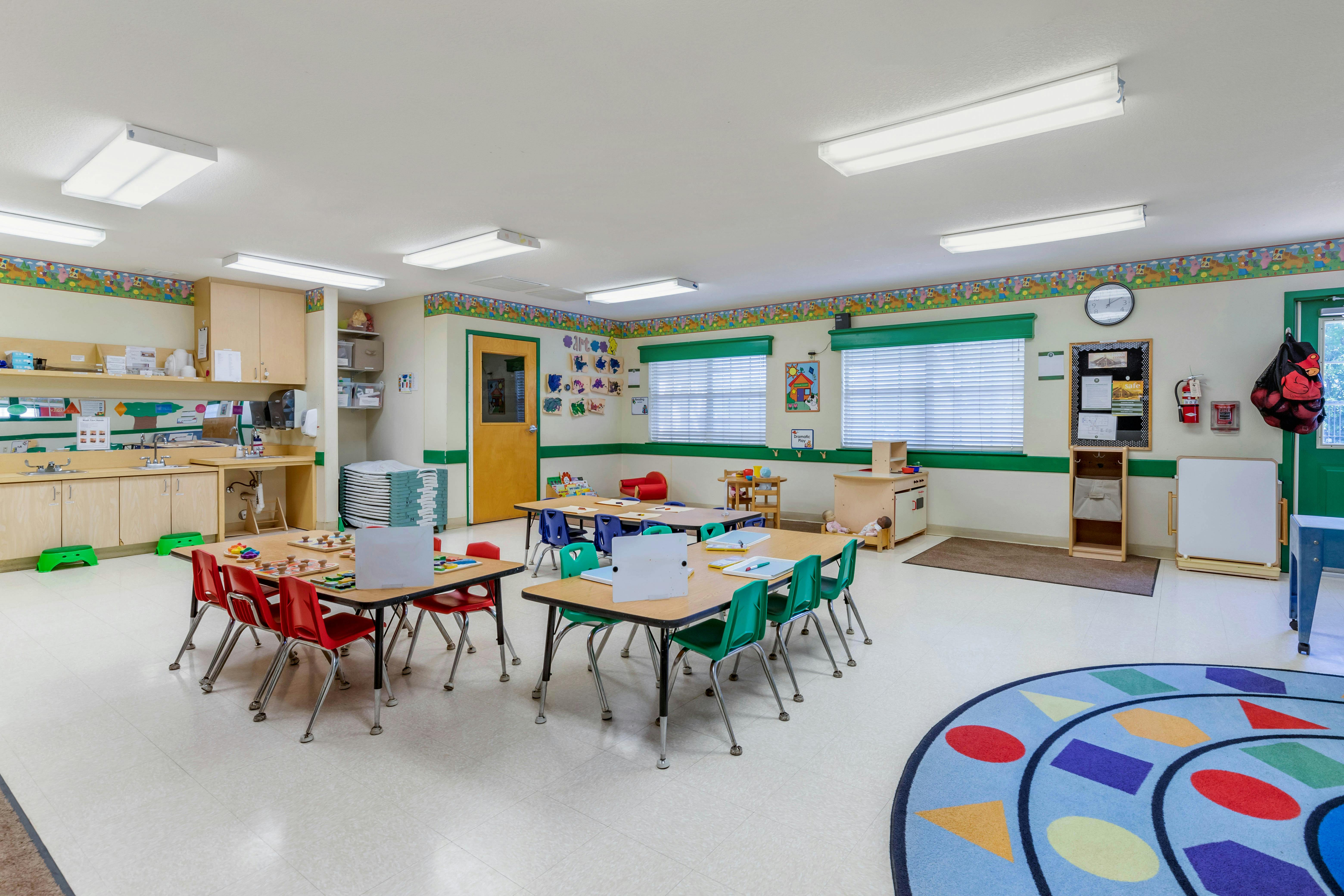An empty early childhood classroom with small tables and chairs