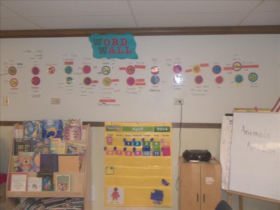 Classroom wall with a "Word Wall" display, calendar, bookshelf, and whiteboard