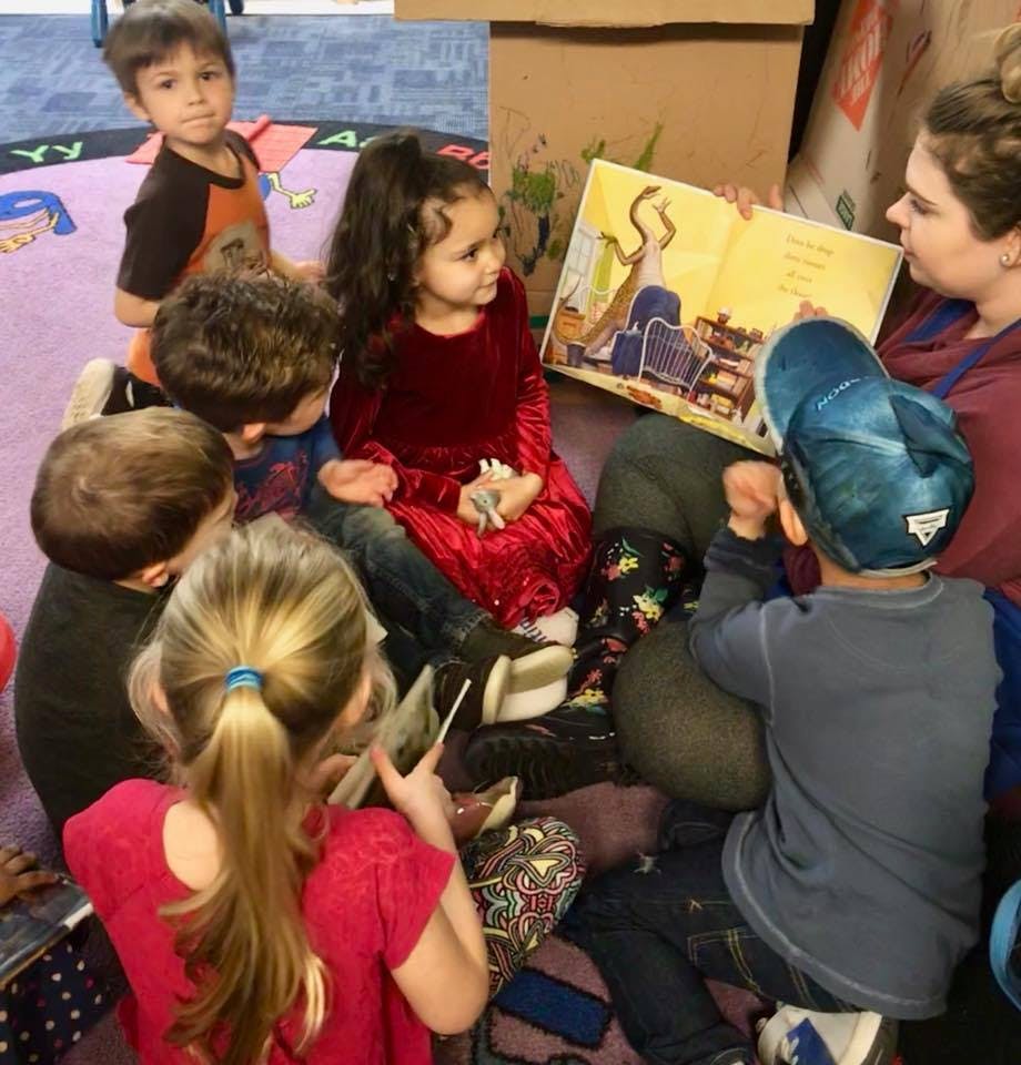 Adult reading a book to a group of children