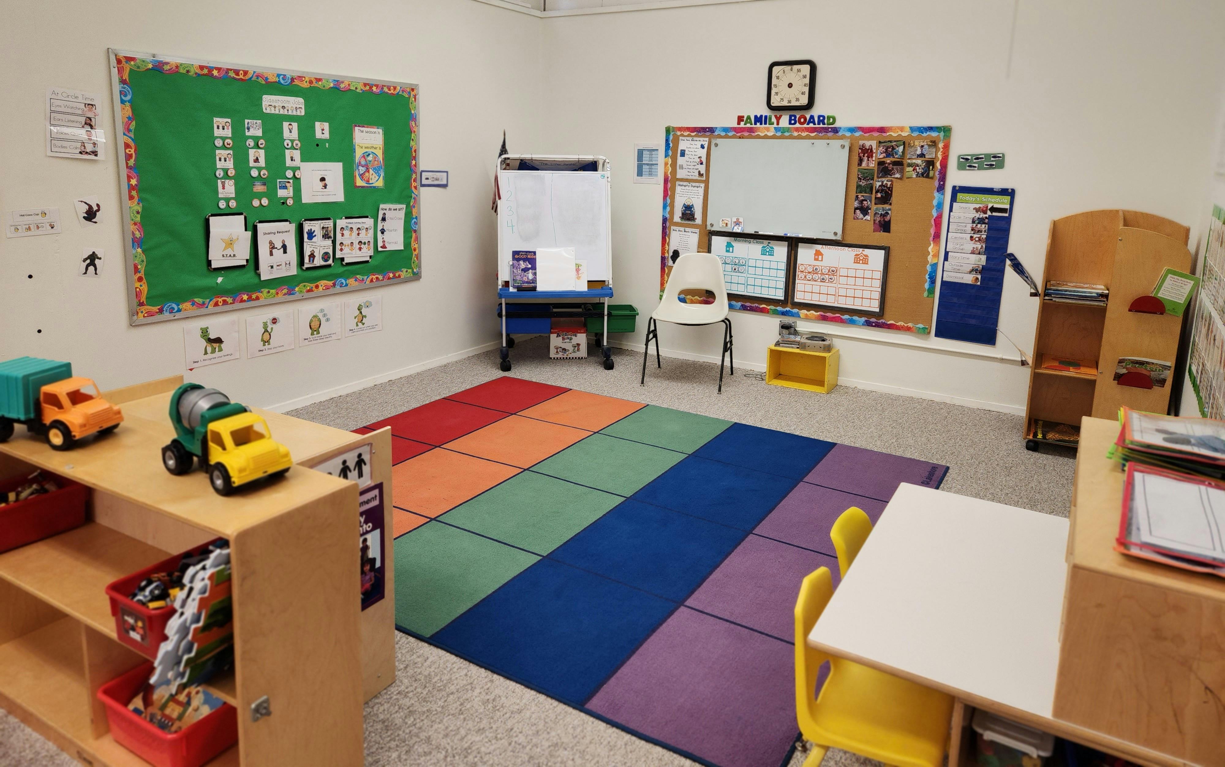 Classroom with a rainbow rug, bulletin boards, and small tables