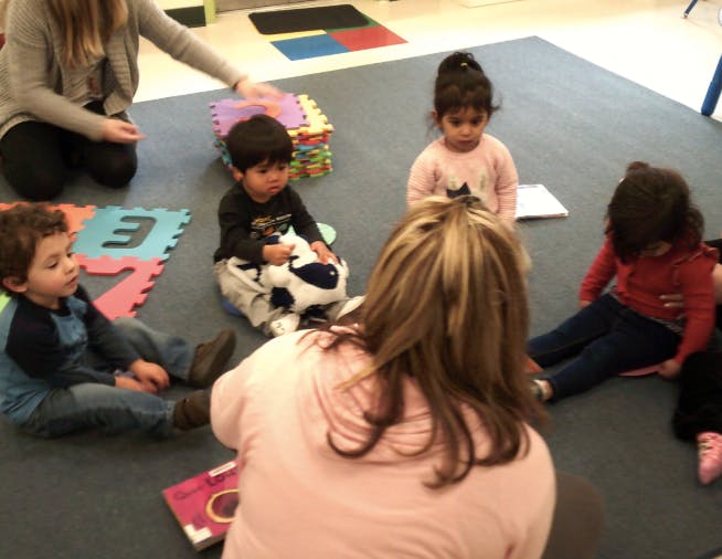 Adults and children sitting on the floor in a classroom