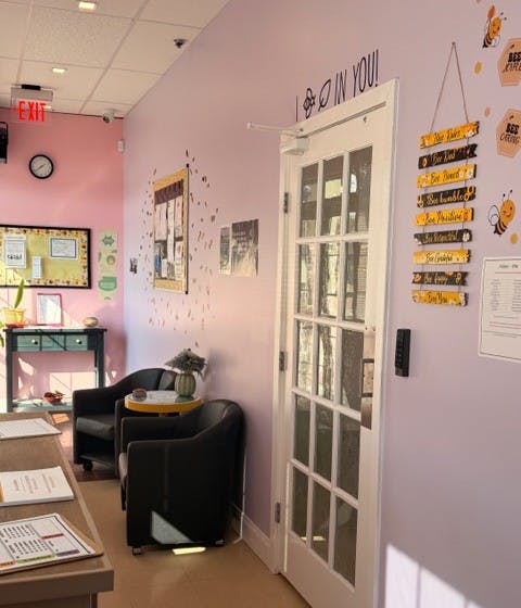 Waiting area with two black chairs, a small yellow table, and a glass-paneled door