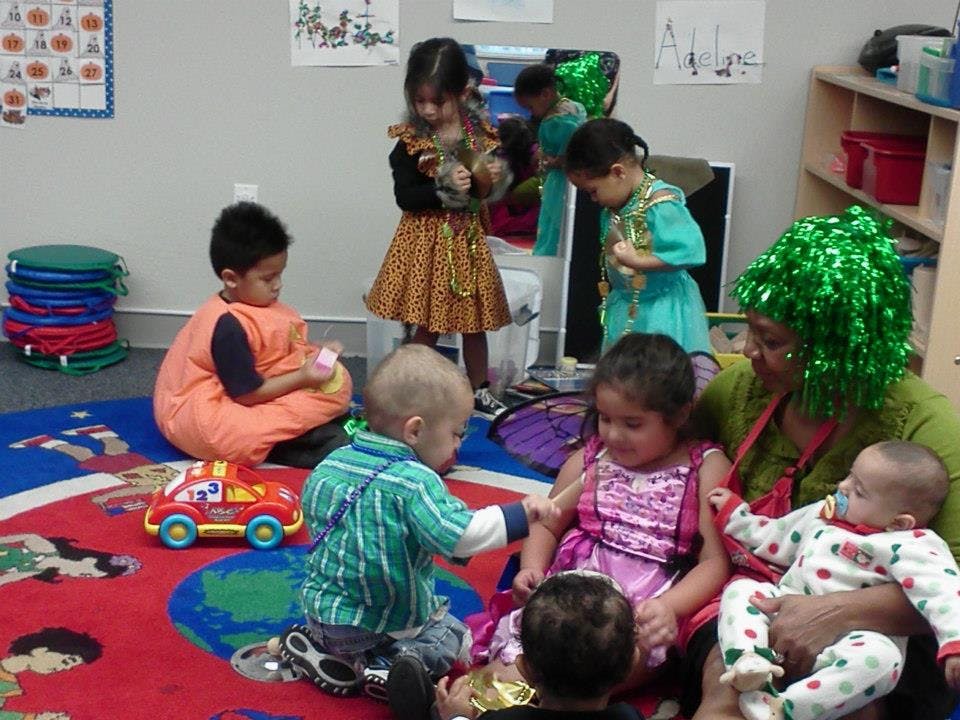 Adult and multiple children playing on a colorful rug