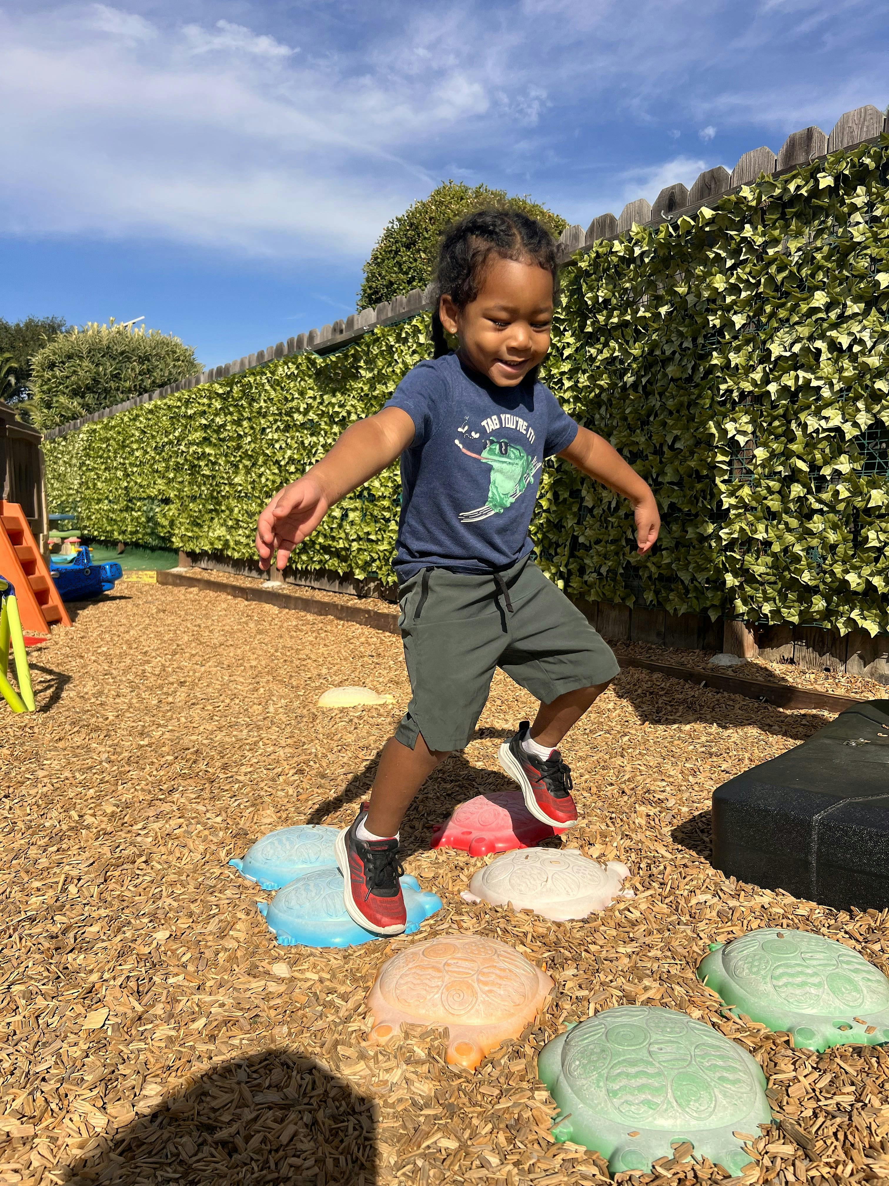 Child balancing on colorful turtle-shaped stepping stones at a playground
