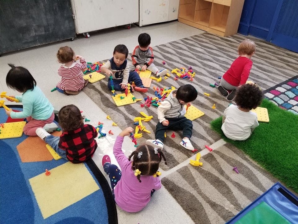 Children playing with toys on a rug in a classroom