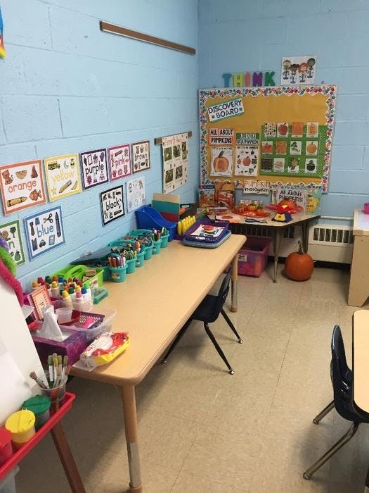 Classroom with long table, art supplies, and bulletin board