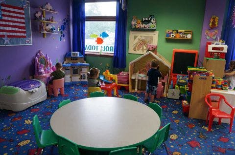 Children playing in a classroom with toys and a round table