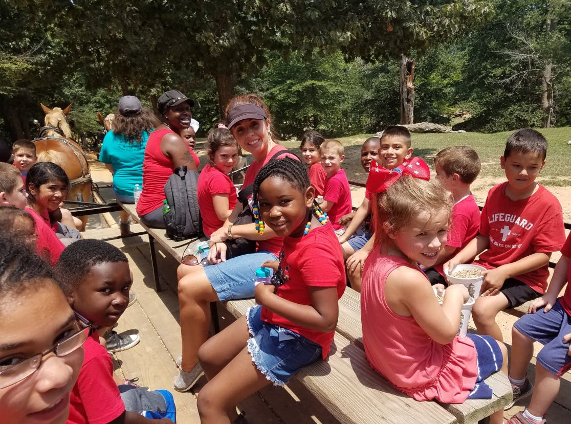 Group of children and adults sitting on benches outdoors